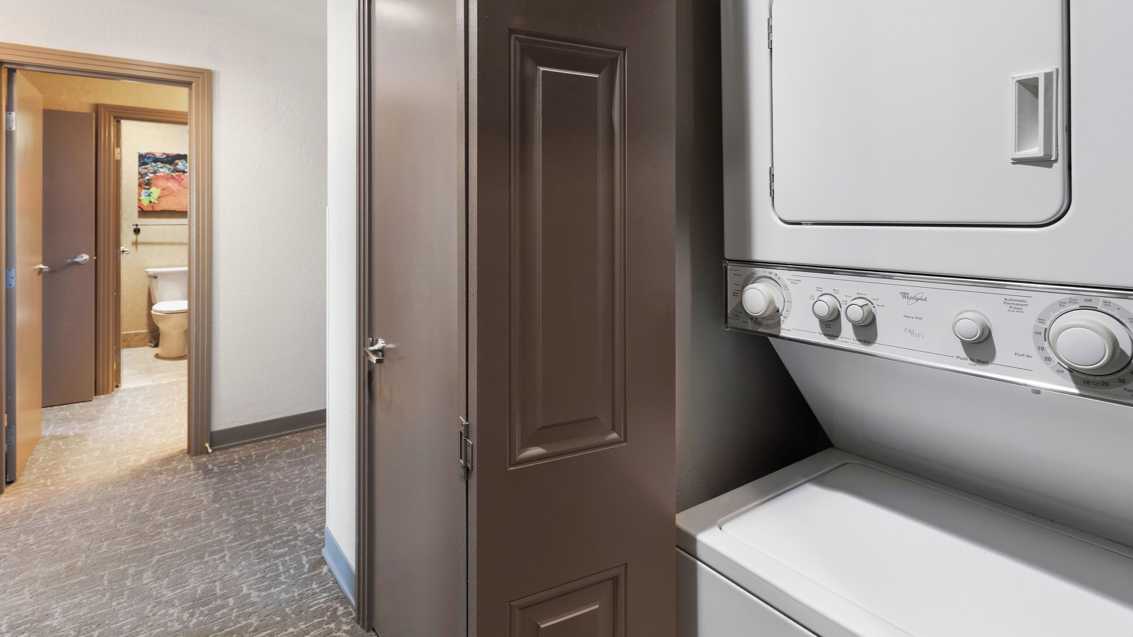 A laundry room with a washer and dryer, a door leading to a bathroom, and a tiled floor.