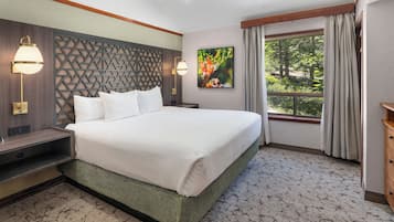 Una habitación de hotel con una cama grande, televisión, ventana con cortinas y un panel decorativo en la pared.