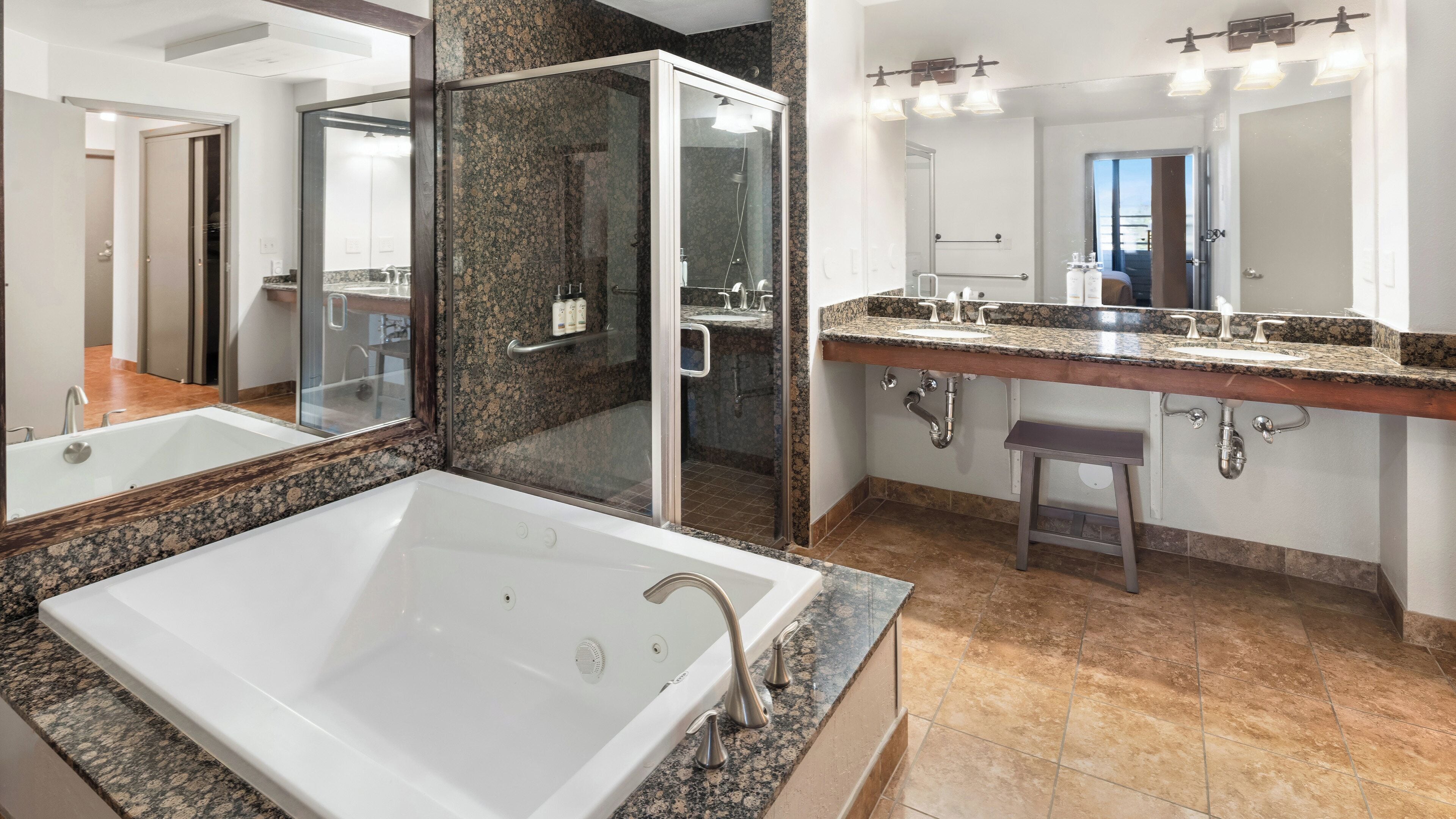 A bathroom with a large bathtub, a shower, and a double sink with a vanity.