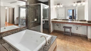 A bathroom with a large bathtub, a shower, and a double sink with a vanity.