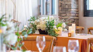 A dining table with a floral centerpiece, candles, and a stone wall in the background.
