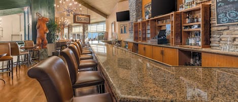 Een bar met leren krukken, een granieten aanrecht en een stenen muur.