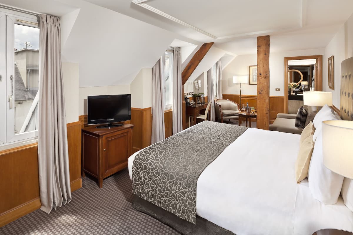 A hotel room with a bed, a TV, a desk, and a chair.