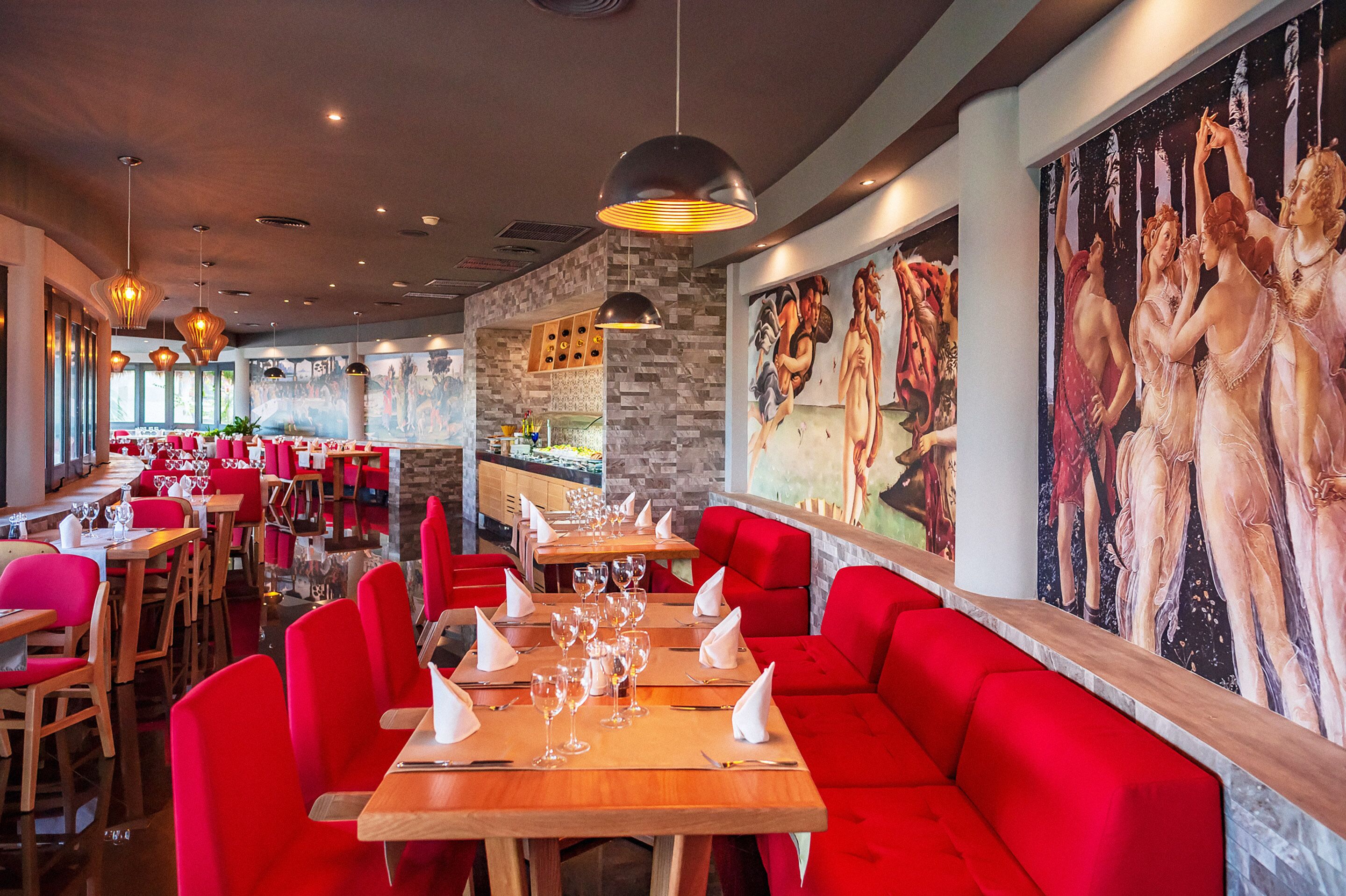 Ein Restaurant mit roten Sitzgelegenheiten, Holztischen und Wandmalerei.