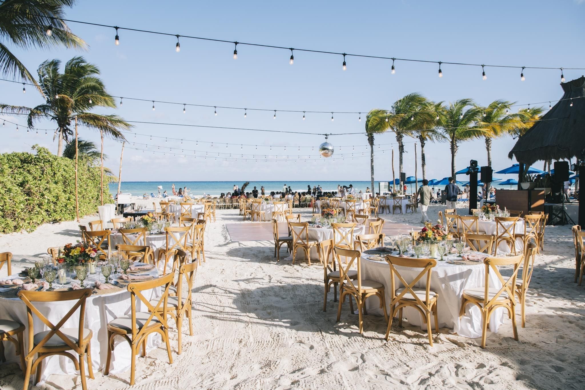 Espaço para casamento ao ar livre, com mesas e cadeiras dispostas na areia, com vista para o mar.