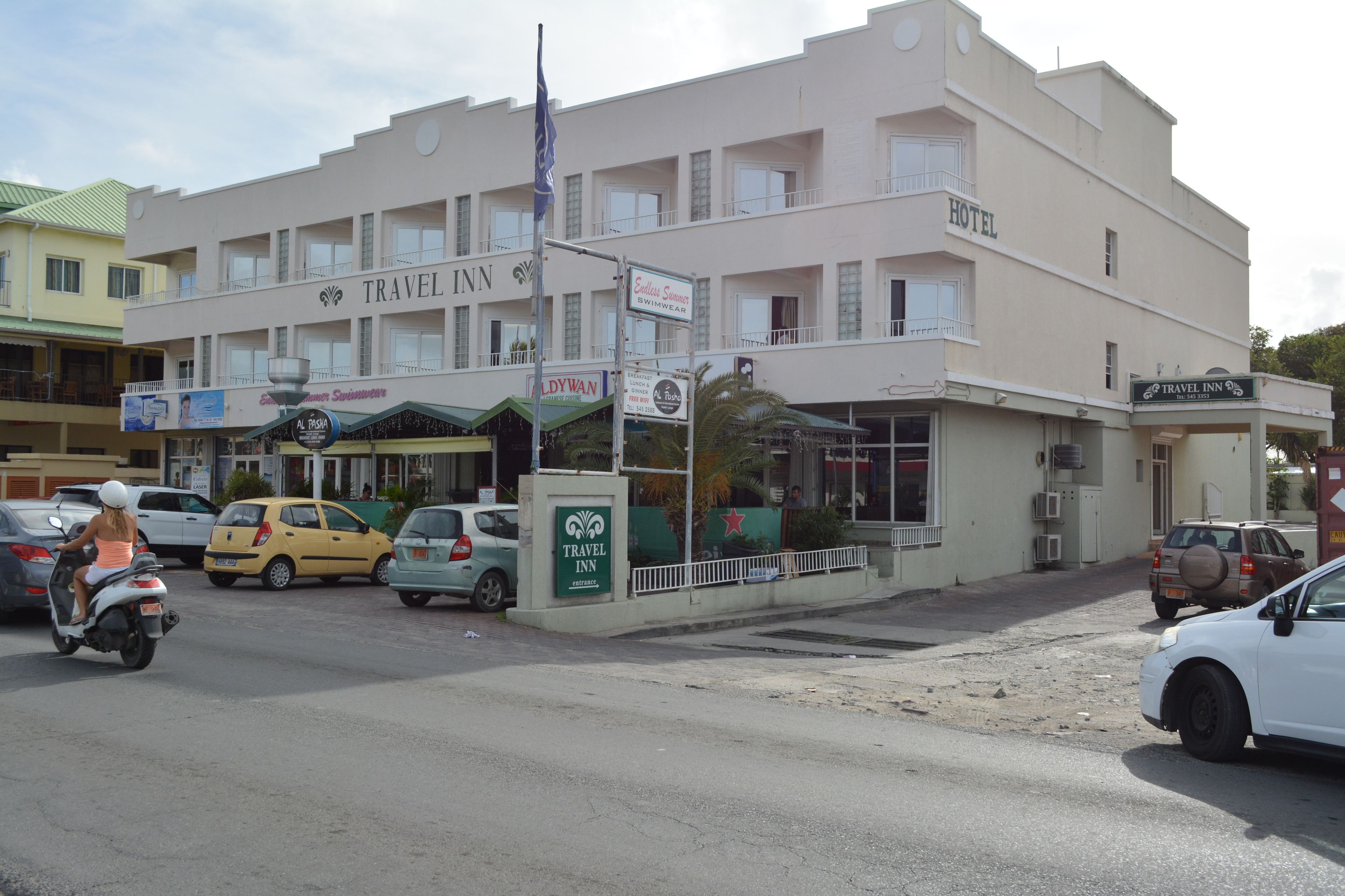 Un edificio a più piani con un cartello che riporta 'Travel Inn' e 'Belly Swimwear'.