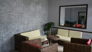 A reception area with a brick wall, a large mirror, and wicker furniture. - Travel Inn Hotel (Simpson Bay)