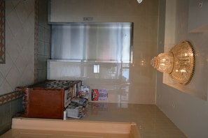 A modern kitchen with a stainless steel range hood, a wooden cabinet, and a wall-mounted light fixture.