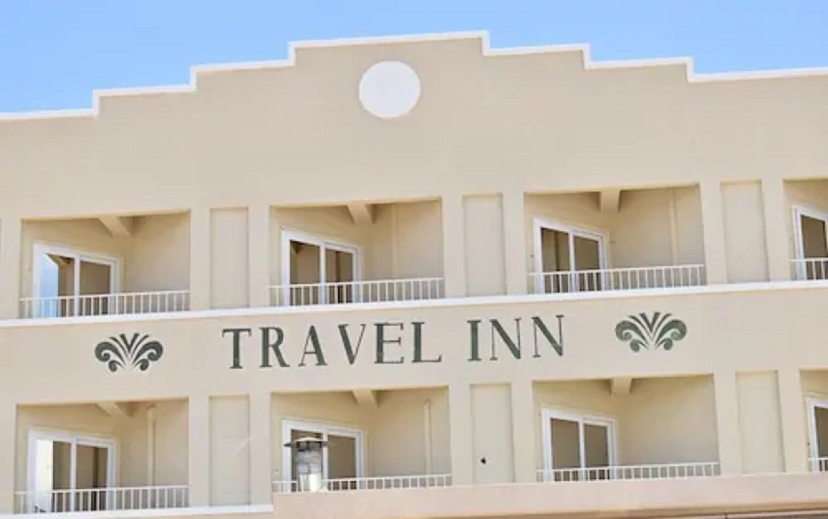 Un edificio con el letrero "TRAVEL INN" que indica que es un hotel.