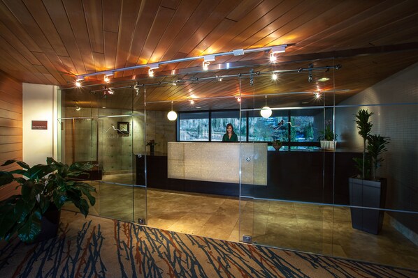 A reception area with a wooden ceiling, glass partitions, and a reception desk. - The Cliff Lodge and Spa (Sandy)