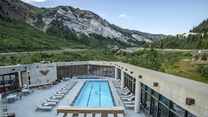 Una piscina en la azotea con sillas de descanso y vistas a las montañas.