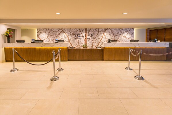 A reception area with a marble counter, a wooden reception desk, and a wall with a tree-like design.