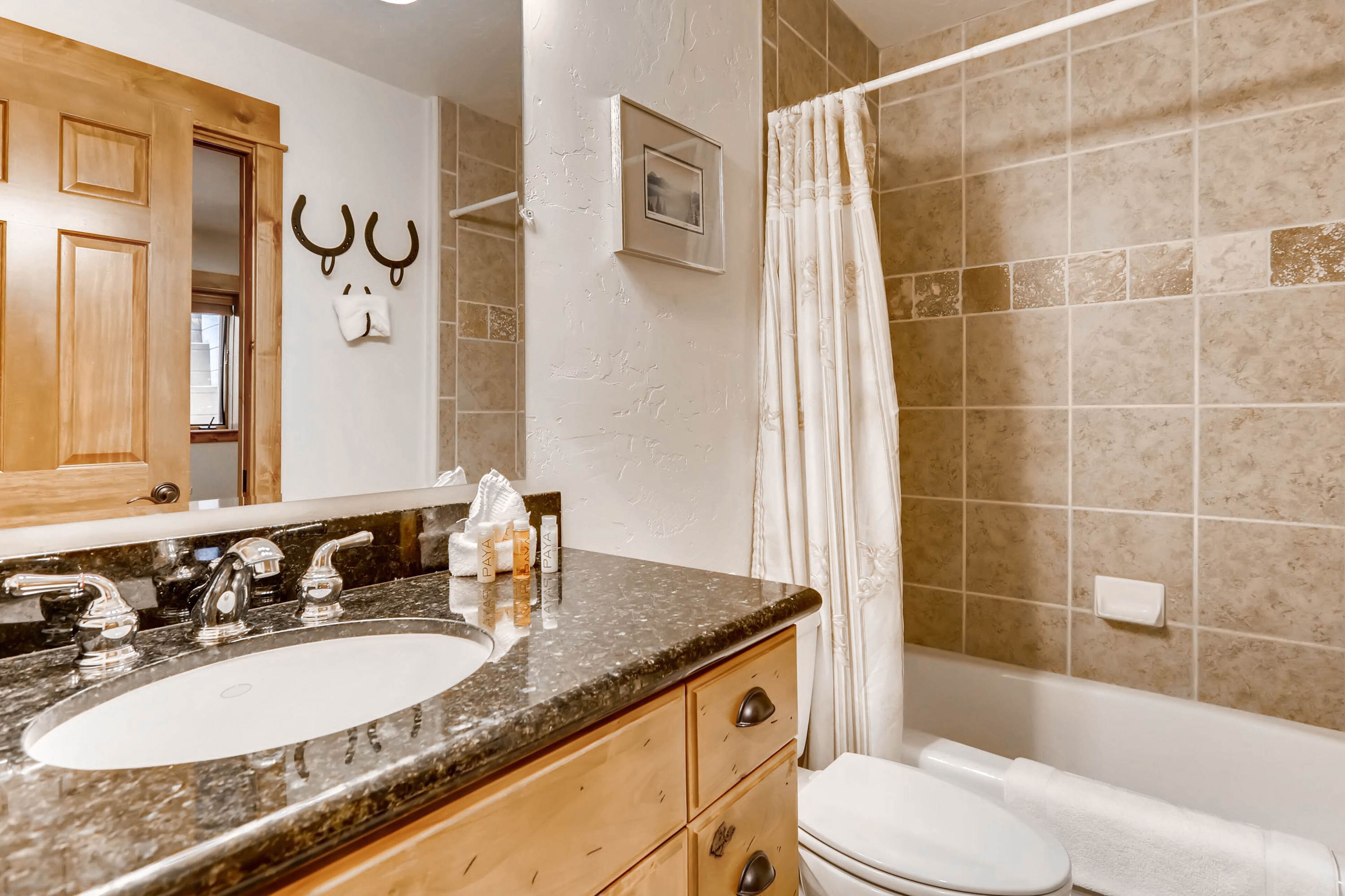 A bathroom with a sink, vanity, and toilet.