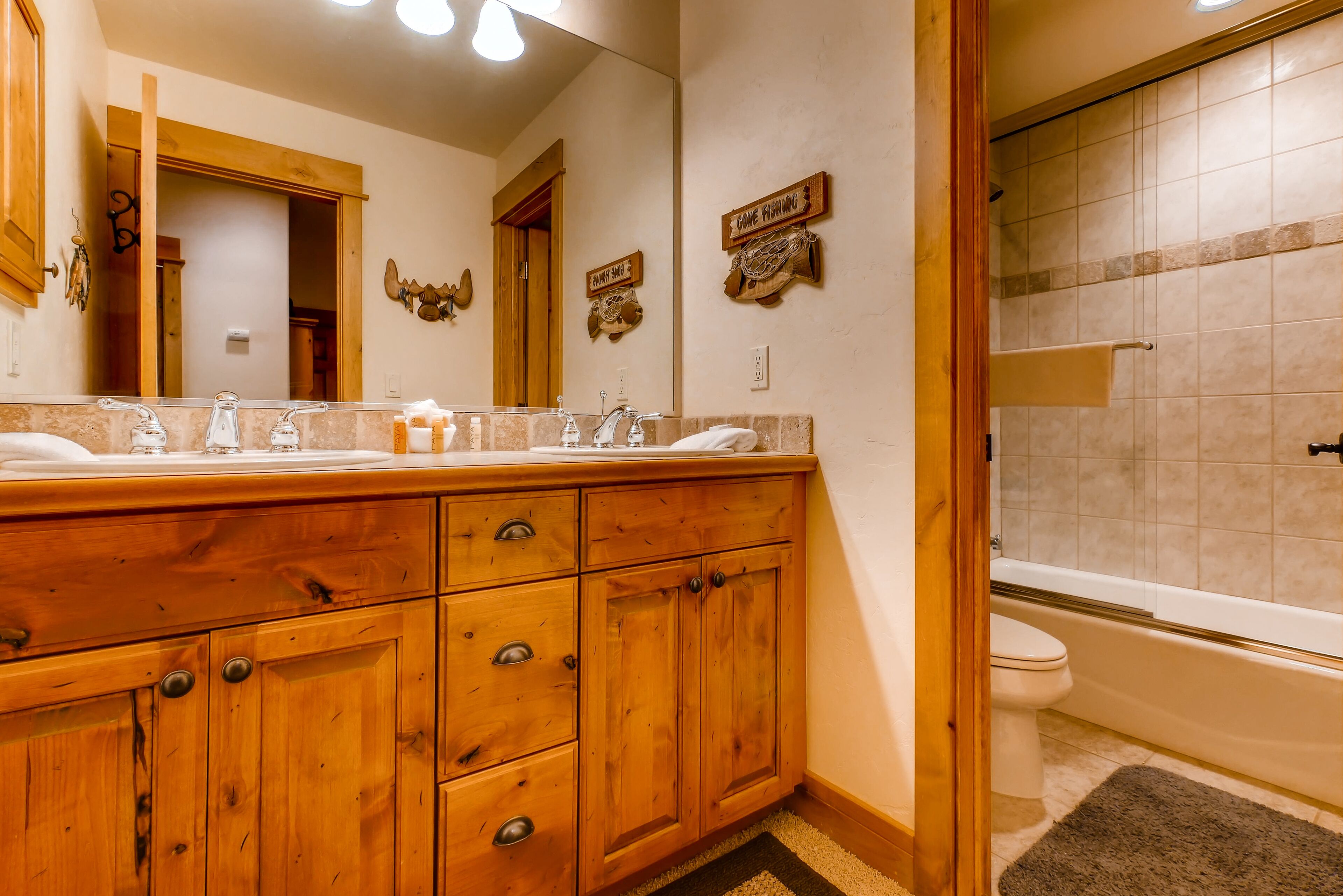 A wooden vanity with a mirror, two sinks, and a towel rack.