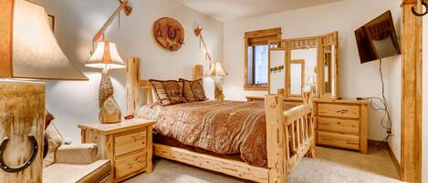 Un dormitorio con una cama de madera, dos mesitas de noche con lámparas, un espejo y un ventilador de techo.
