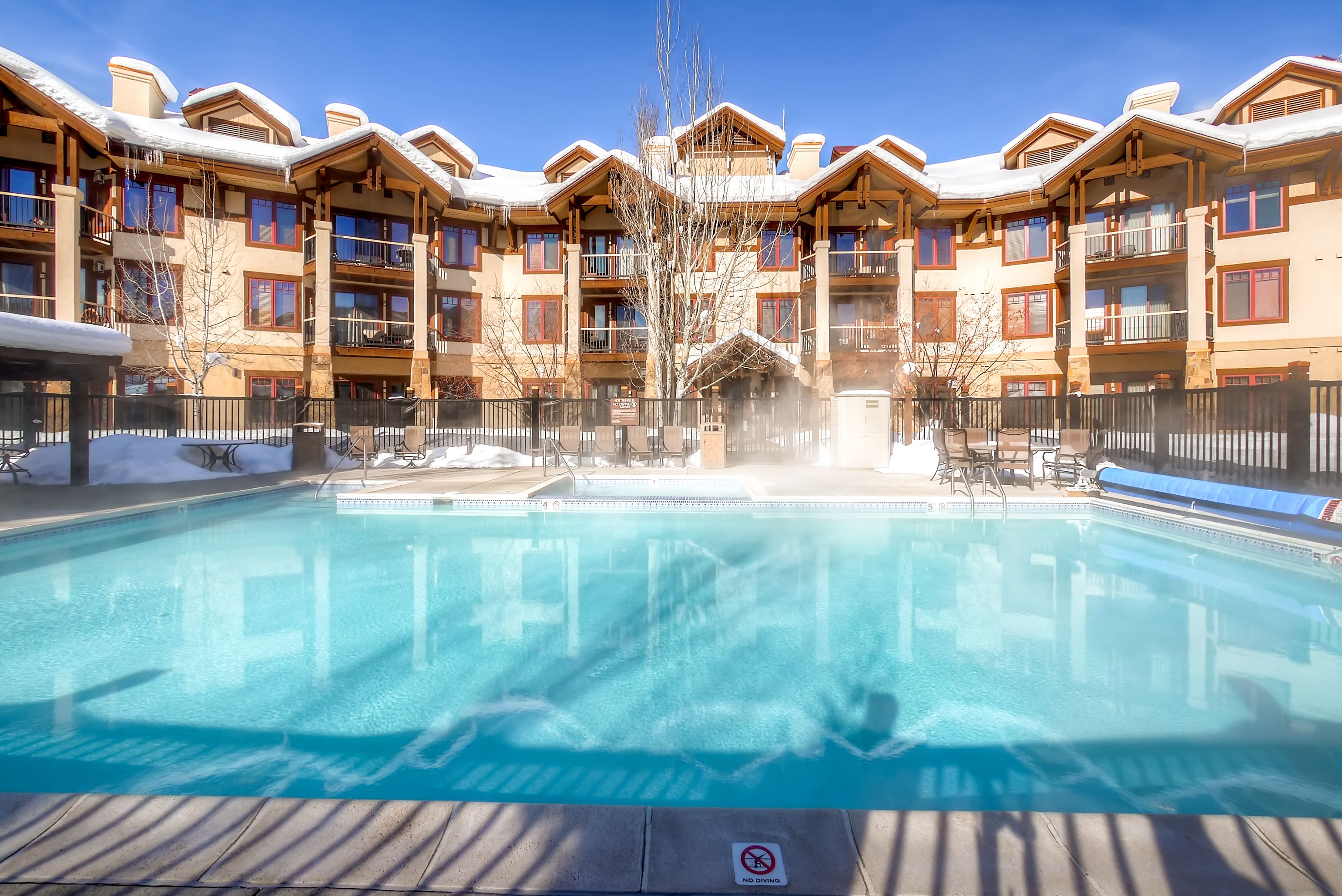 Un hotel amb piscina, balcons de fusta i neu al terrat.