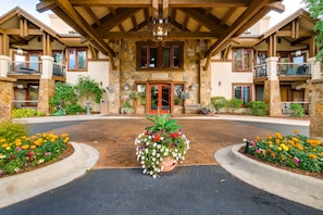 A stone building with a central entrance, balconies, and flower beds.