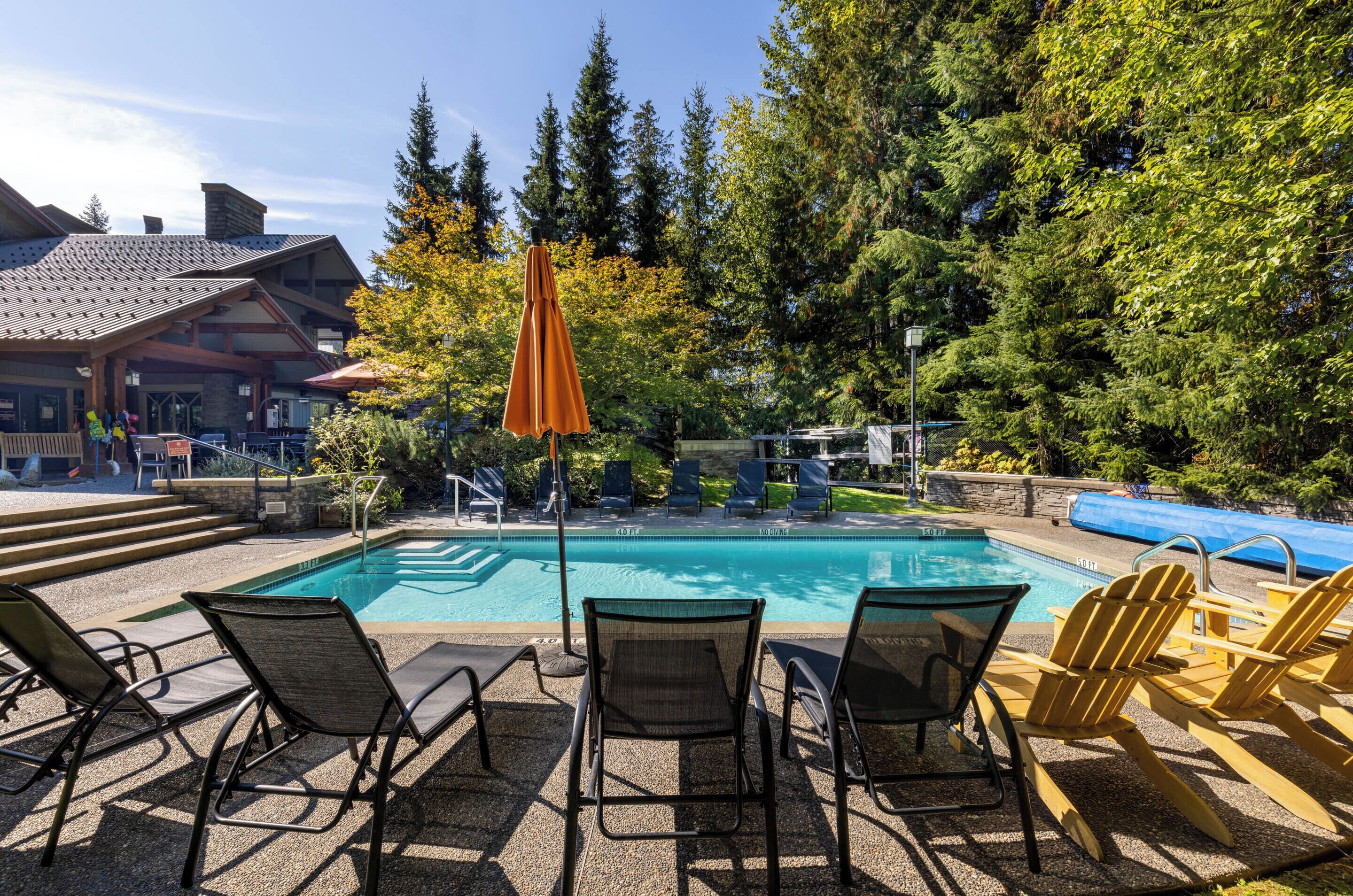 A pool area with lounge chairs and a wooden deck.