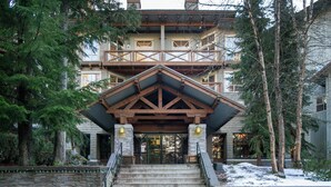 A multi-story building with a stone facade, wooden balcony, and a staircase leading to the entrance. - Horstman House by Whistler Premier (Whistler)
