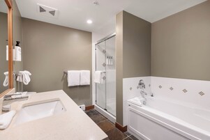Un baño moderno con una bañera grande, una ducha con cerramiento de vidrio y un tocador con lavabo y espejo.