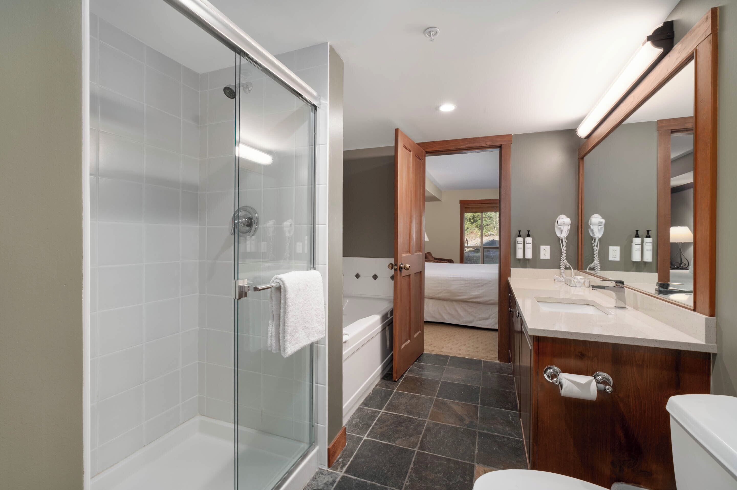 Un baño moderno con ducha envuelta en vidrio, bañera, tocador con espejo y retrete.