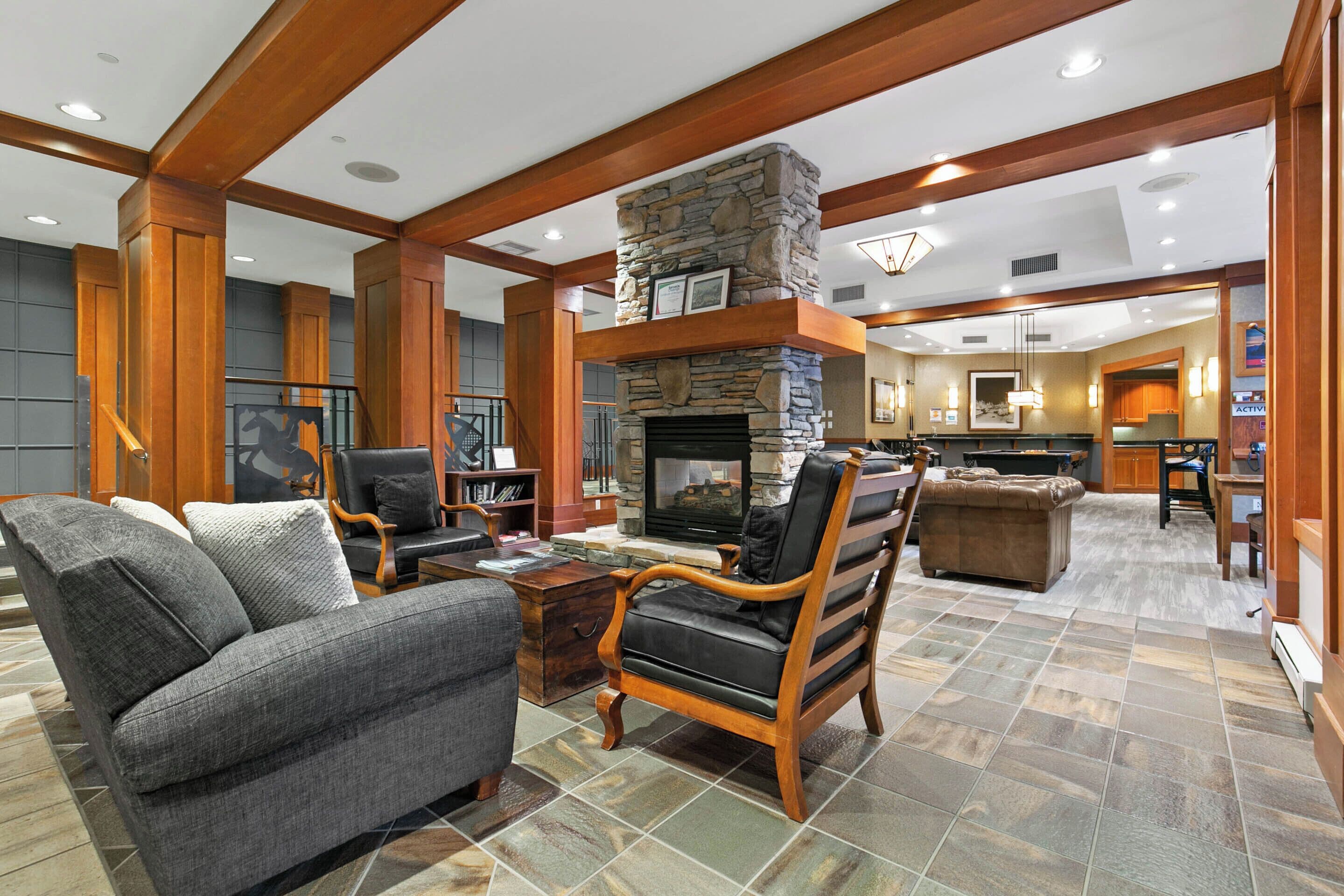 A spacious living area with a stone fireplace, wooden beams, and a television.