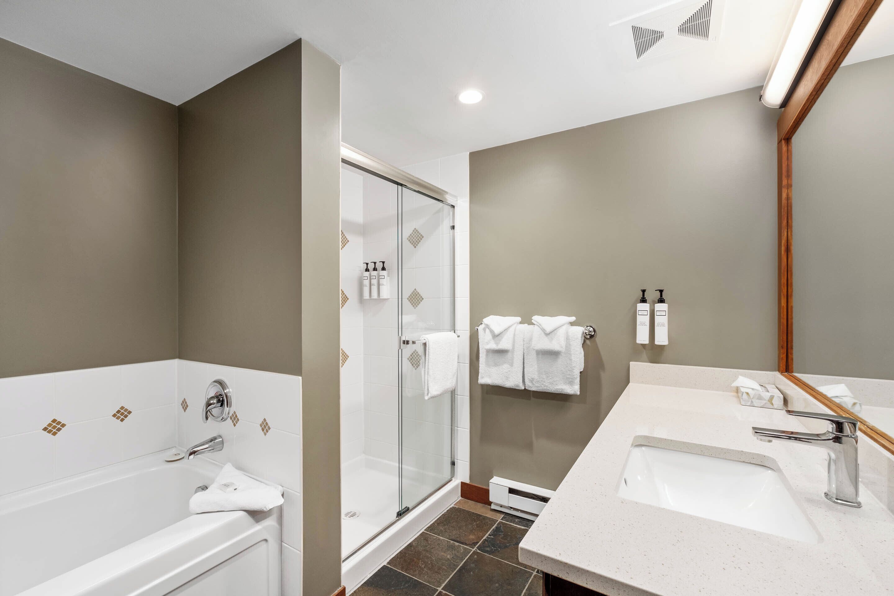 A modern bathroom with a bathtub, shower, and sink.