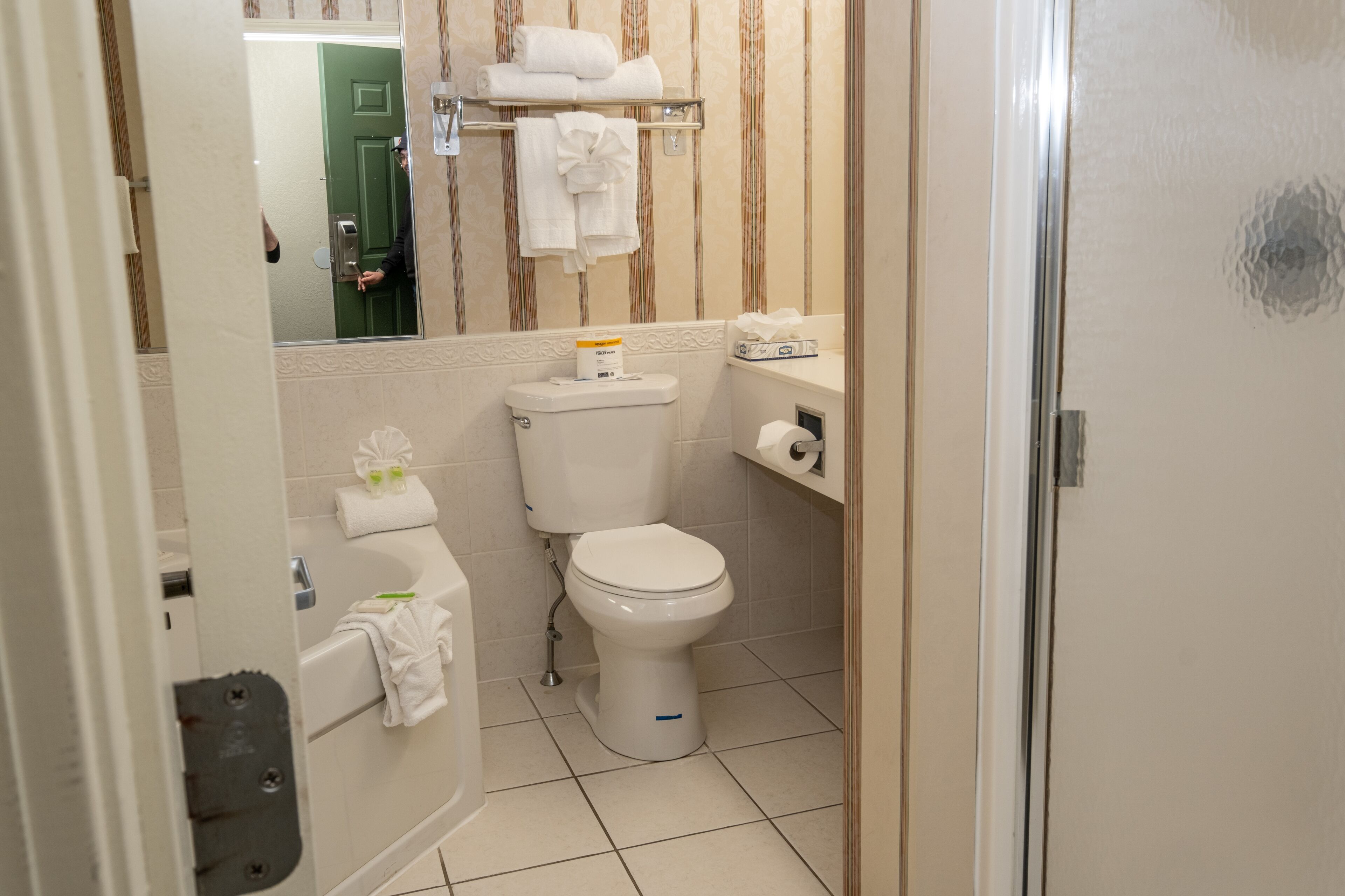 Une salle de bain équipée de toilettes, d’une baignoire, d’un porte-serviettes et d’un miroir.