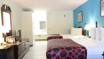 A hotel room with a bed, bedside table, lamp, dresser, and a mirror.