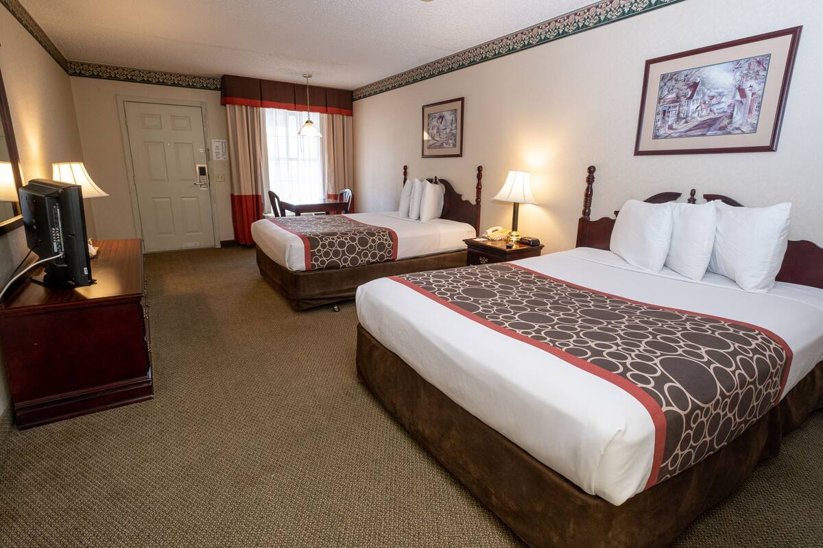 Una habitación de hotel con dos camas, televisión, escritorio y una silla.