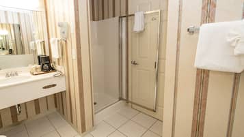 A bathroom with a shower, a sink with a coffee maker, and a mirror.