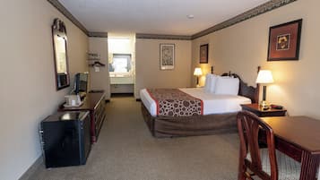 Habitación de hotel con cama, escritorio, silla y espejo.