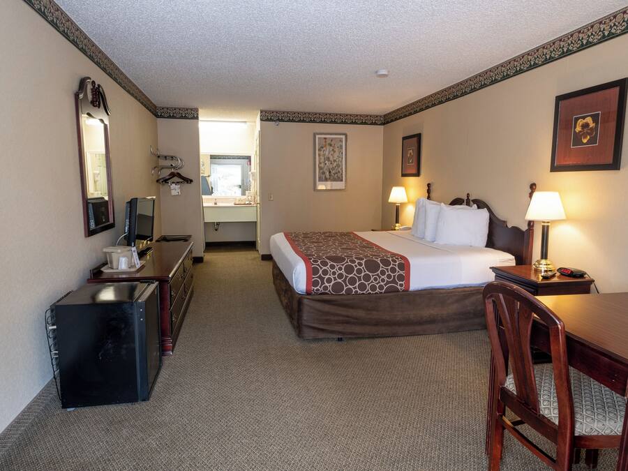 Habitación de hotel con cama, escritorio, silla y espejo.