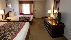 Quarto de hotel com duas camas, cômoda, televisão e janela com cortinas.