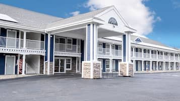 Stylish two-story motel with a central entrance and covered walkway, featuring a symmetrical facade and peaked roof.
