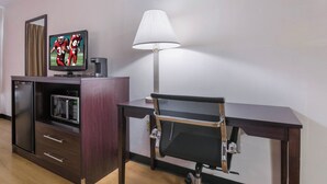 A hotel room with a television, a lamp, a desk, and a chair. - Red Roof Inn Carrollton (Carrollton)