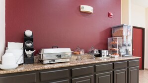 A kitchen counter with various food items and appliances, including a coffee machine, a bread dispenser, and a toaster. - Red Roof Inn Carrollton (Carrollton)