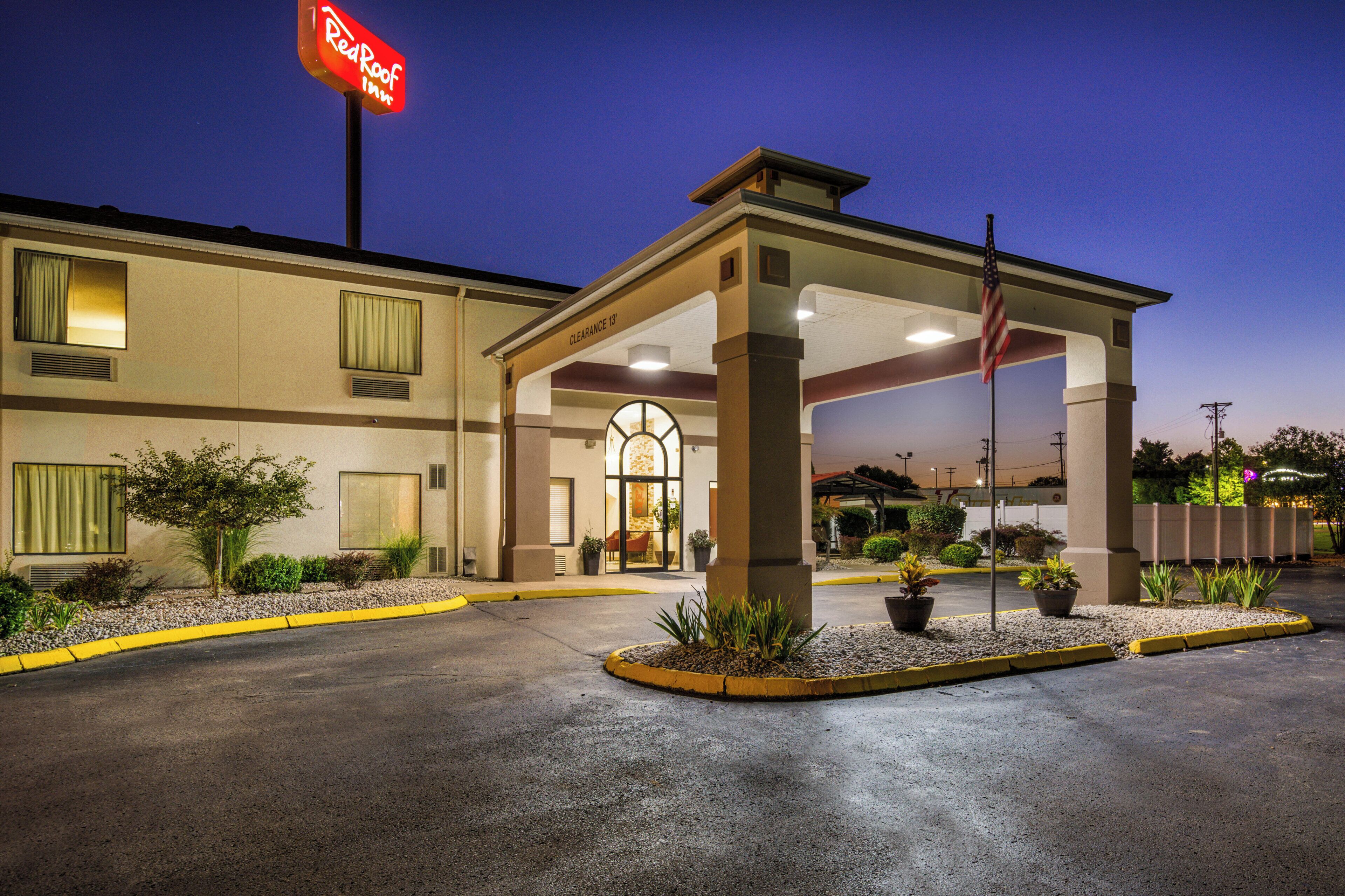 A hotel entrance with a covered waiting area, a flag, and a sign indicating a clearance of 13 feet.