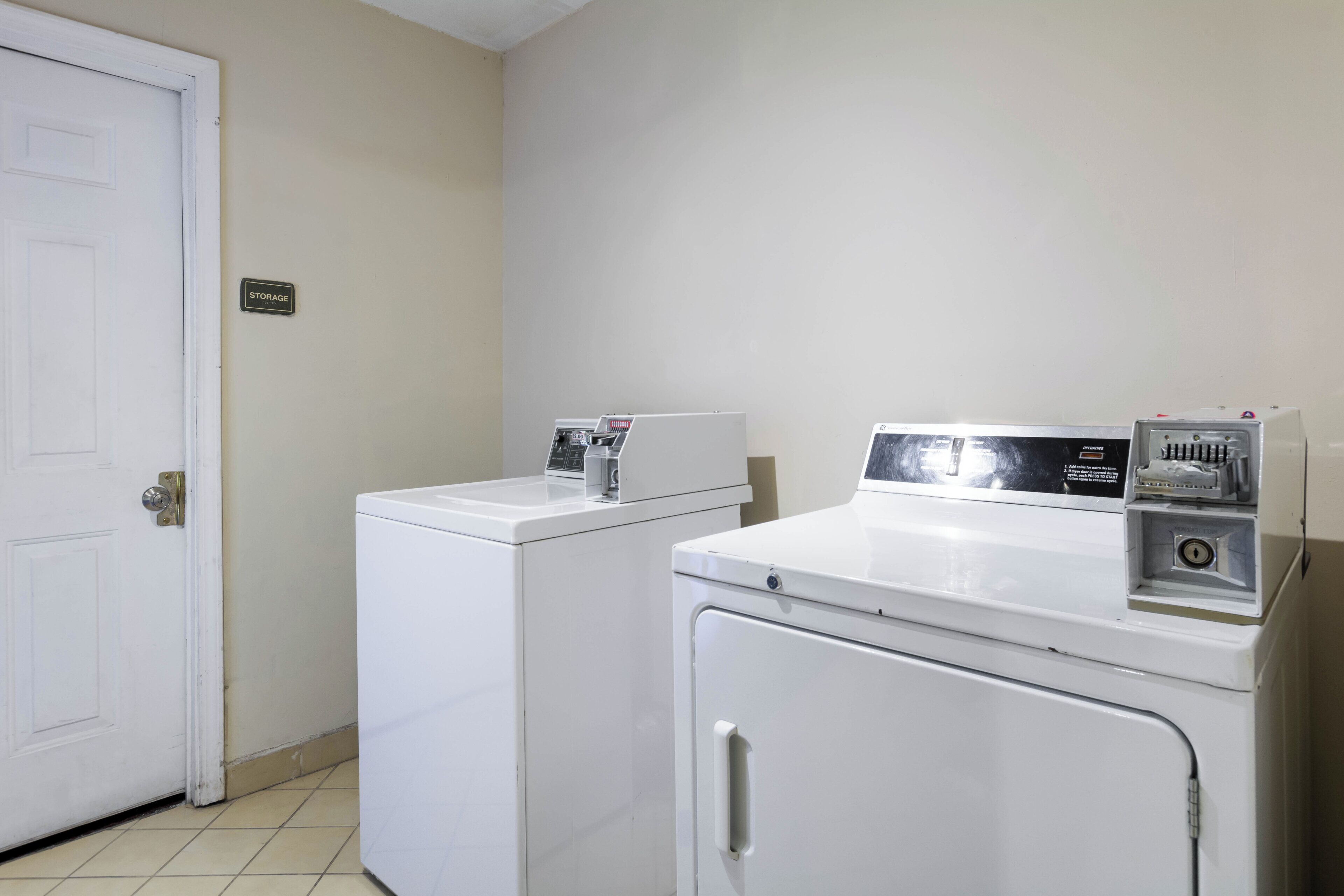 A laundry room with two white washing machines and a door.