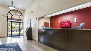 A reception area with a digital display indicating free Wi-Fi availability, a reception desk, and a door leading outside. - Red Roof Inn Carrollton (Carrollton)