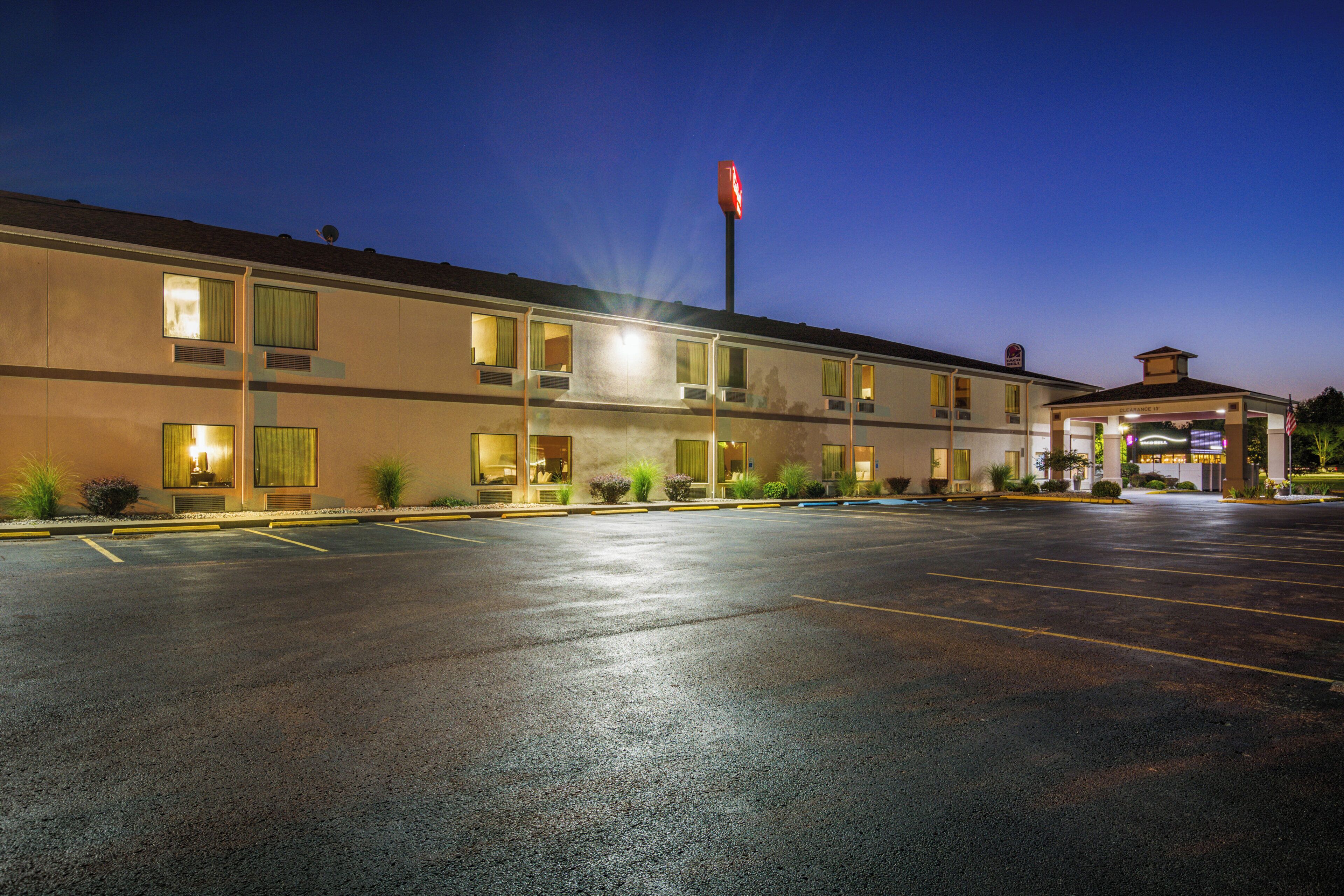 Un motel con parcheggio, diverse finestre e il cartello di un Taco Bell.