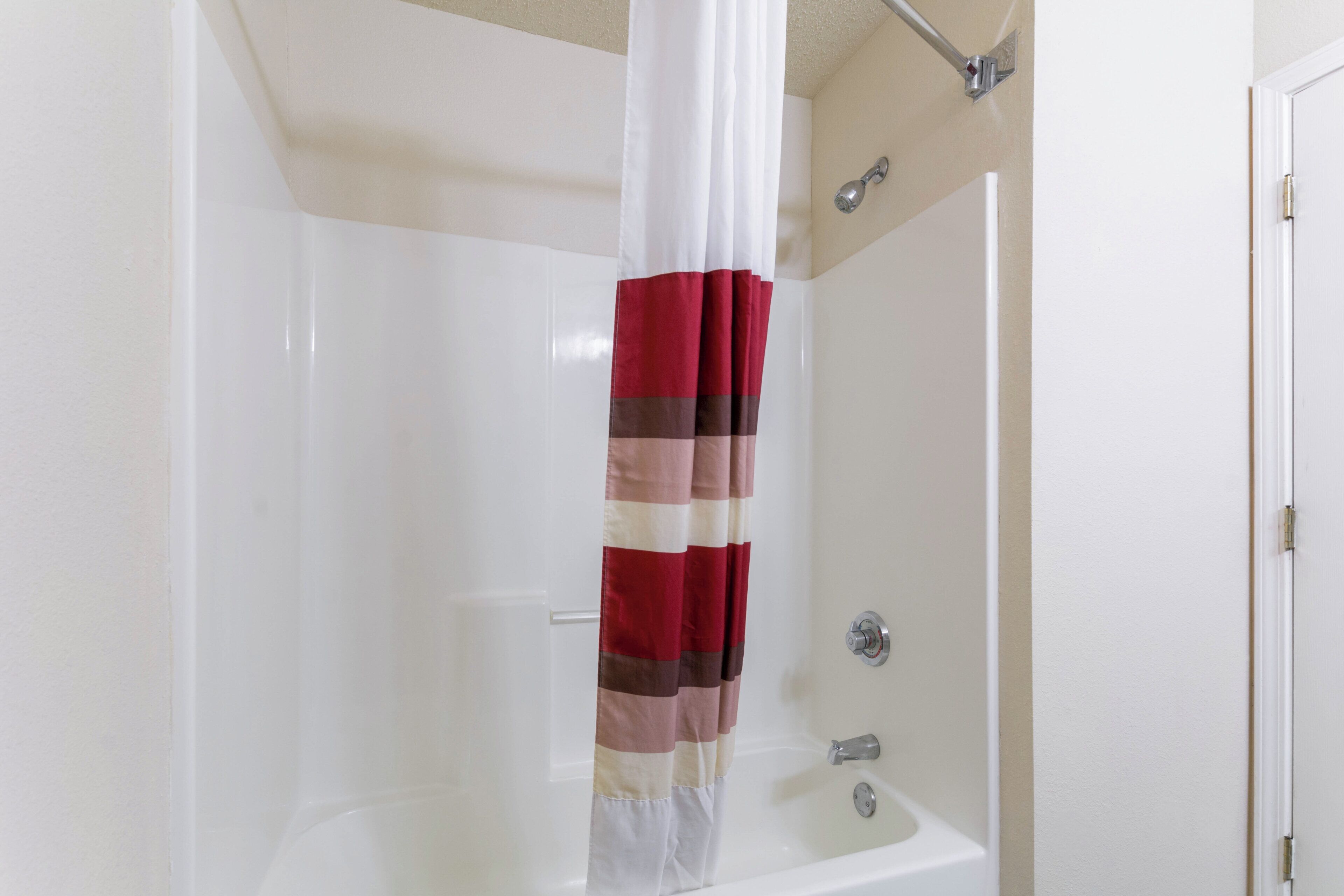 A bathroom with a shower curtain, a bathtub, and a toilet.