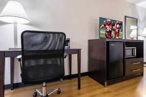 A hotel room with a desk, a chair, a television, a microwave, and a cabinet. - Red Roof Inn Carrollton (Carrollton)