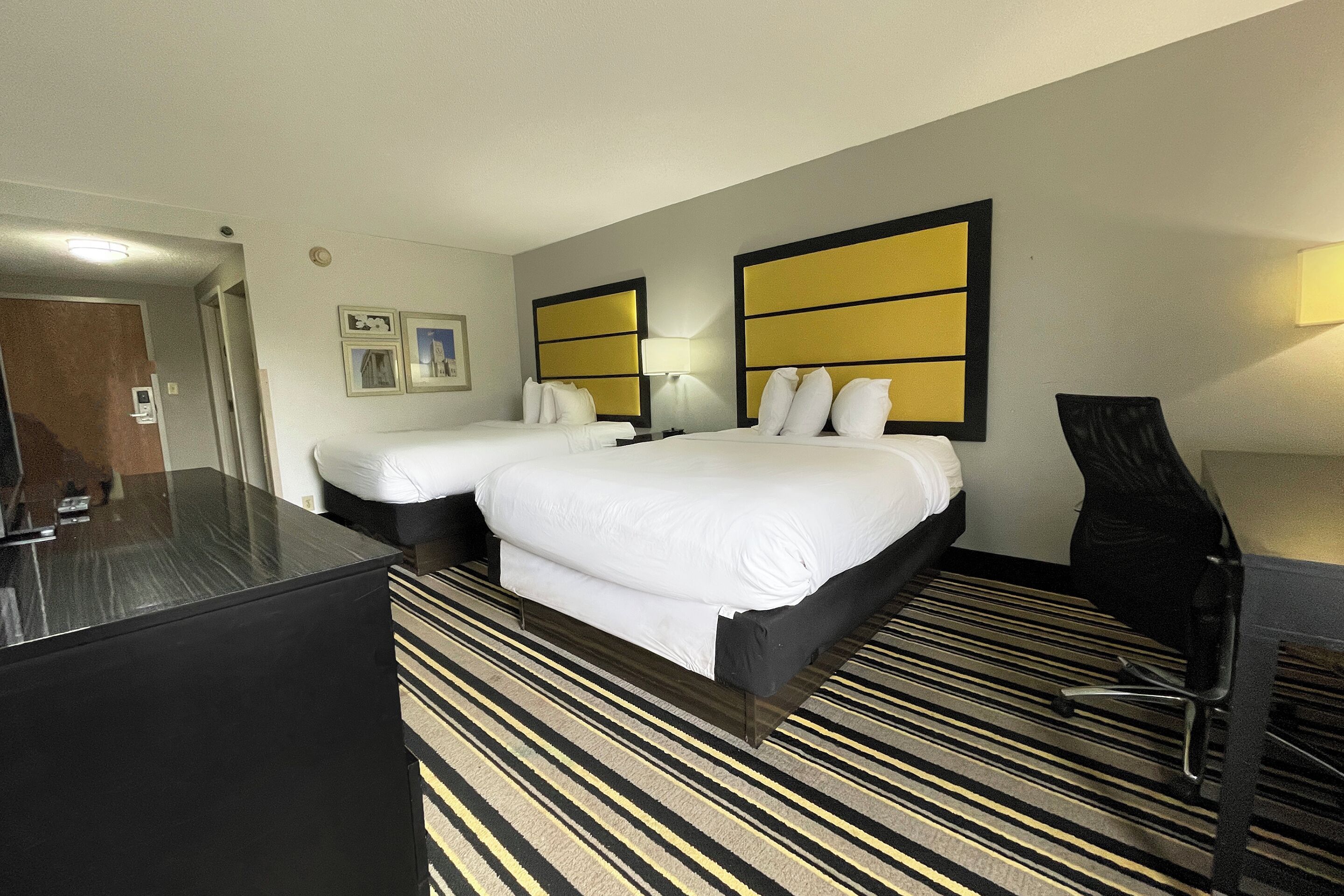 Ein Hotelzimmer mit zwei Betten, einem Schreibtisch und einem Sessel.