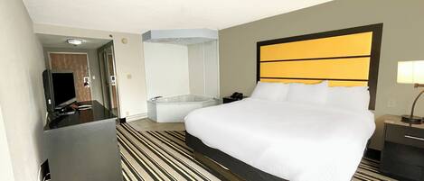 Une chambre d’hôtel dotée d’un grand lit, d’un téléviseur à écran plat, d’un bureau, d’une chaise, d’un miroir et d’une salle de bain avec baignoire et douche.