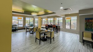 Un amplio comedor con varias mesas y sillas, ventanas grandes y vistas al exterior.