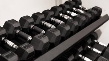 A rack of black hexagonal dumbbells with visible weight markings.