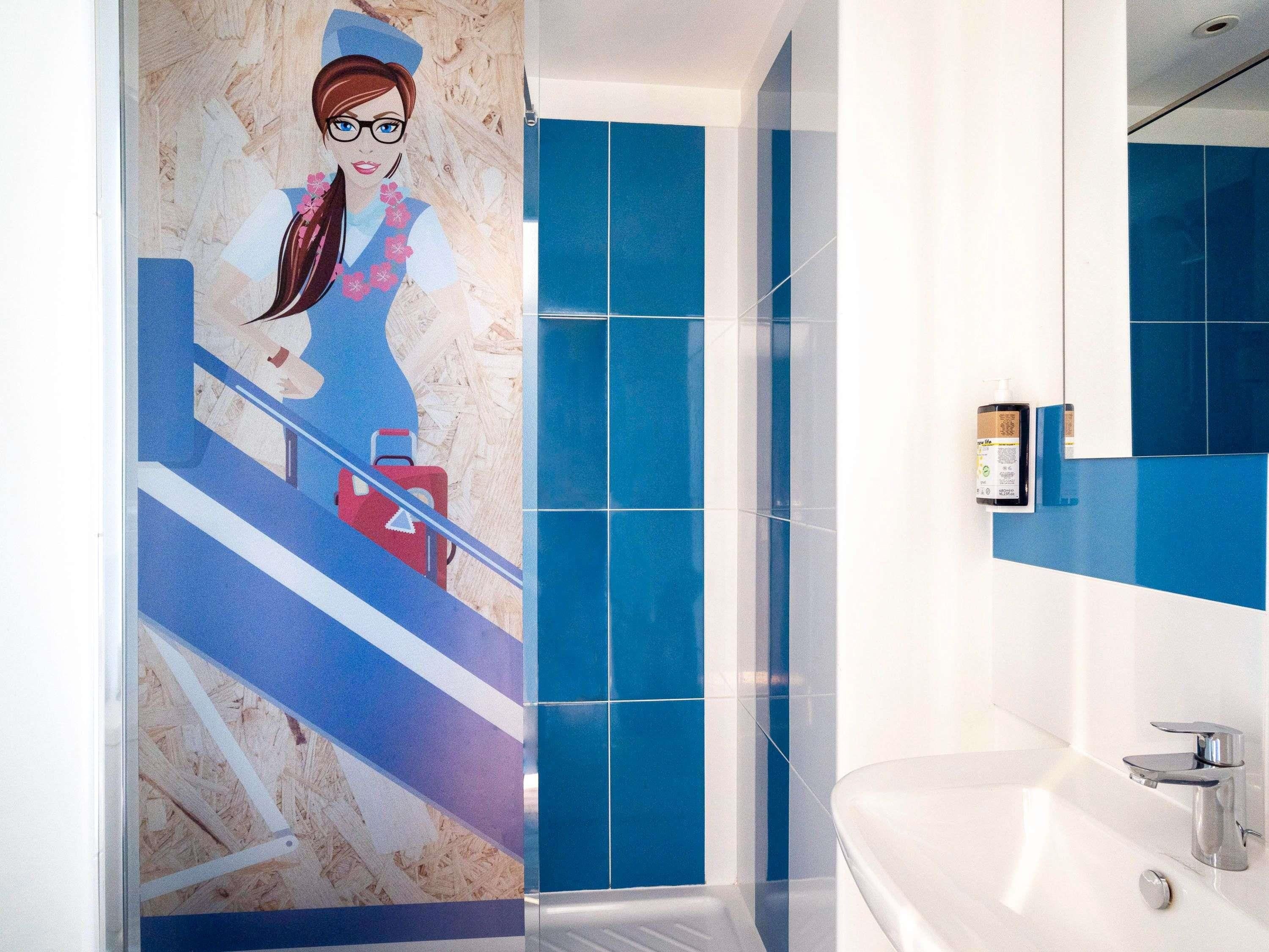 A modern bathroom with a large mirror, a white bathtub, and blue tiles.