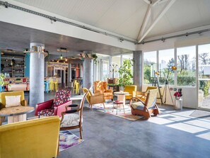 Un hall d’entrée spacieux, doté de meubles modernes, de grandes fenêtres et d’un coin bar.