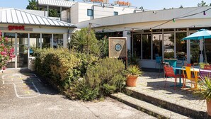 A hotel with a 'greet' sign, outdoor seating, and a dartboard. - greet Hotel Bordeaux Aeroport (Merignac)